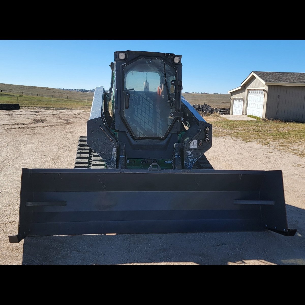 John Deere 331G compact track loader with 108-inch snow pusher, head-on view